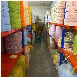 Rolls on racking beside the cutting tables, one bin per colour.